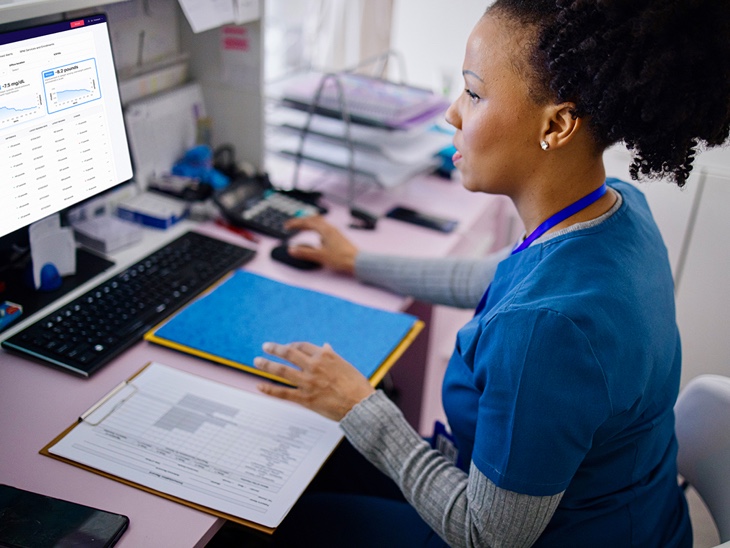 Nurse at desk monitoring patient dashboard