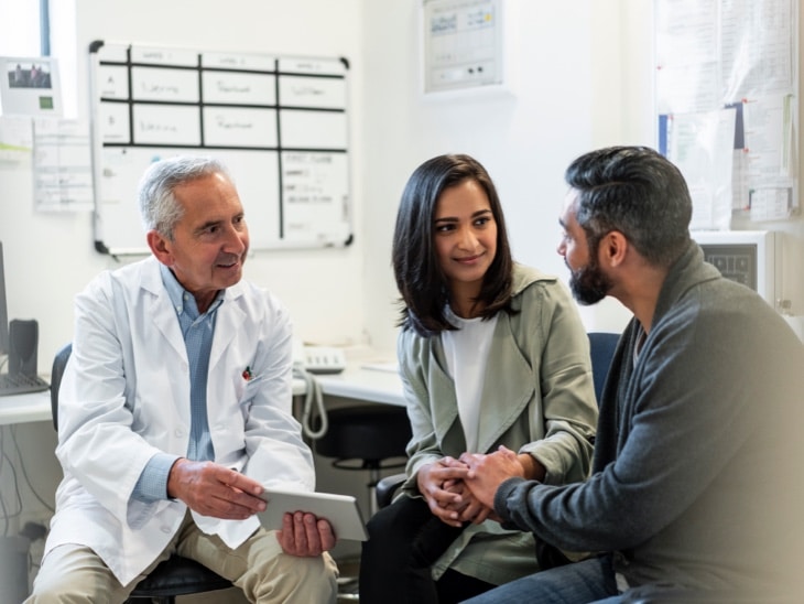 Doctor Discussing With Couple Over Digital Tablet