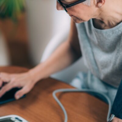 Woman taking blood pressure and checking results on phone