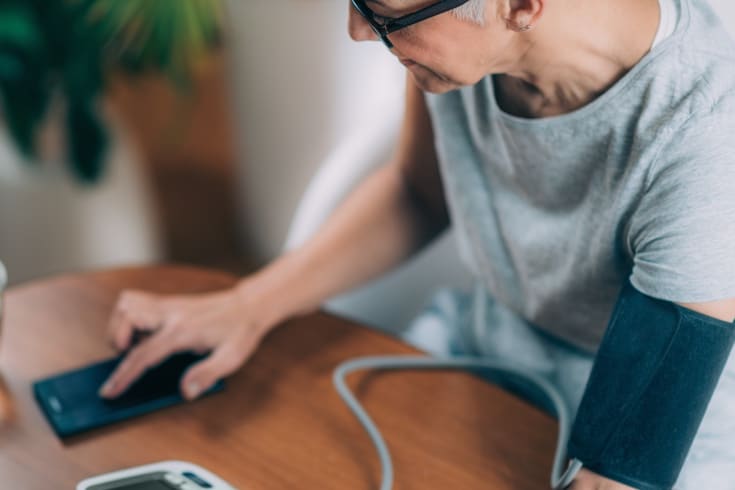 Woman taking blood pressure and checking results on phone